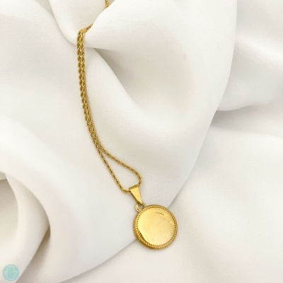 Colar dourado com pendente redondo sobre tecido branco