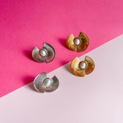 Quatro brincos metálicos com pérolas em fundo rosa