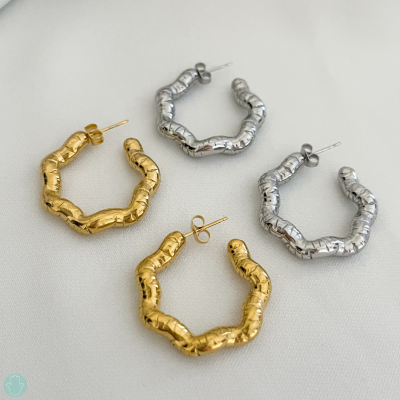 Quatro pares de brincos de argola texturizados em prata e dourado sobre fundo claro