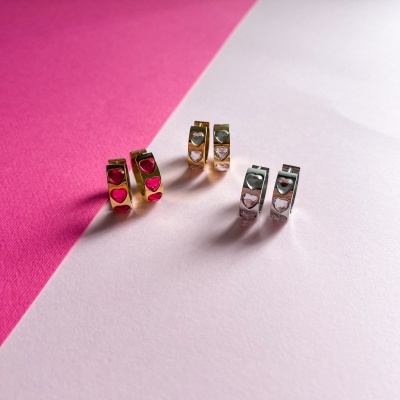 Três pares de brincos pequenos de argola em metal, dourados e prateados, com corações decorativos