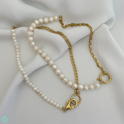 Colar de pérolas com correntes douradas sobre tecido branco