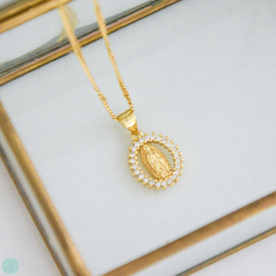 Colar de ouro com pendente oval e pedras brancas em superfície branca