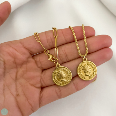 Colar dourado com medalhões redondos em mão sobre fundo claro