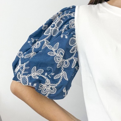 Manga balão azul com bordados brancos numa peça de roupa branca
