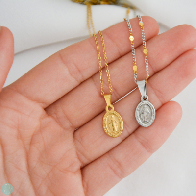 Colares com medalhões de Nossa Senhora em dourado e prateado sobre a mão