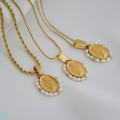 Três colares dourados com pendentes ovais religiosos e pedras brancas