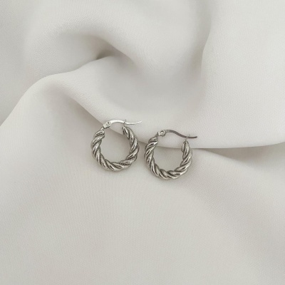 Brincos de argola torcidos em metal prateado sobre tecido branco