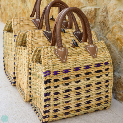 Sacos de palha com alças de couro castanho junto a parede