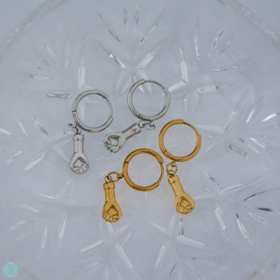 Conjunto de quatro argolas douradas e prateadas com pendentes em forma de punho fechado sobre vidro facetado