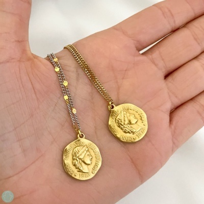 Colares com medalhões dourados e correntes em prata e dourado na mão.