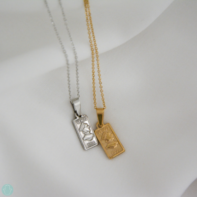 Colares dourado e prateado com pendentes retangulares gravados com touro VERSO 1980 em tecido branco