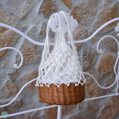 Garrafa branca em rede macramé com base em vime castanho pendurada em estrutura metálica branca