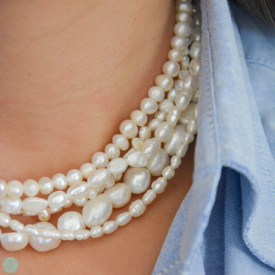 Colar de pérolas brancas em várias voltas e camisa de ganga azul clara