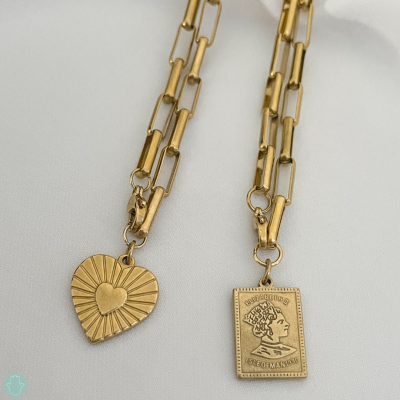 Colares dourados com pendentes de coração e moeda sobre fundo branco