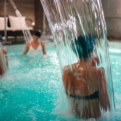 Piscina interior com cascatas de água e pessoas a relaxar