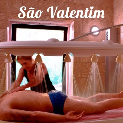 Mesa de massagem com chuveiros a jorrar água e terapeuta a massajar homem deitado