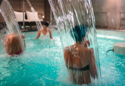 Piscina interior com cascatas de água e pessoas a relaxar