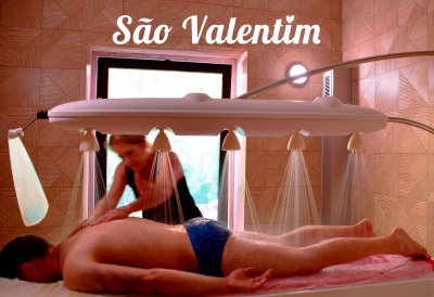 Mesa de massagem com chuveiros a jorrar água e terapeuta a massajar homem deitado