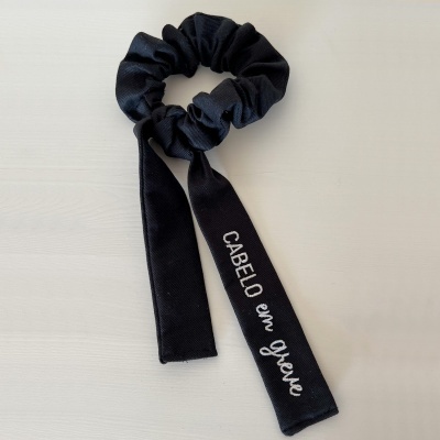 Elástico de cabelo preto com fitas e texto CABELO em greve bordado em branco