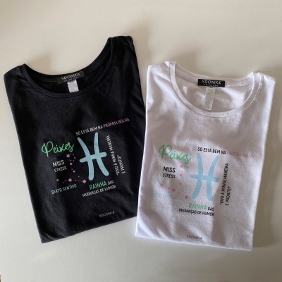 Dois t-shirts, preto e branco, com estampas coloridas do signo Peixes e texto em português