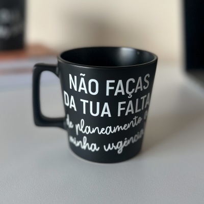 Caneca preta com texto em português sobre superfície clara