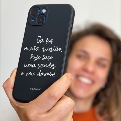 Capa de telemóvel preta com texto em branco e uma pessoa ao fundo desfocada