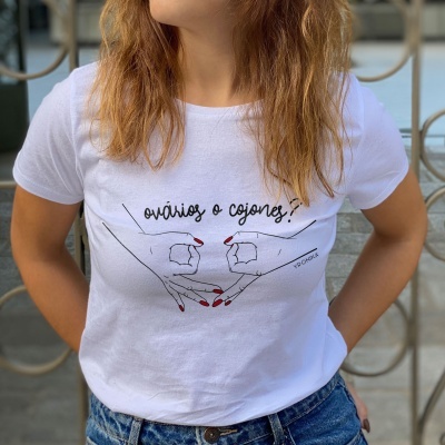 T-shirt branca com ilustração e texto 'ovários e cojones!' com mãos desenhadas
