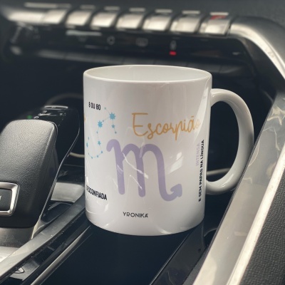 Caneca branca com alça e design decorativo, na consola central de carro