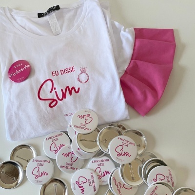 T-shirt branca e rosa com texto e botons relacionados a madrinhas