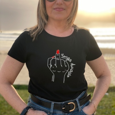 T-shirt preta com estampa de mão a mostrar dedo médio e texto, mulher ao ar livre.