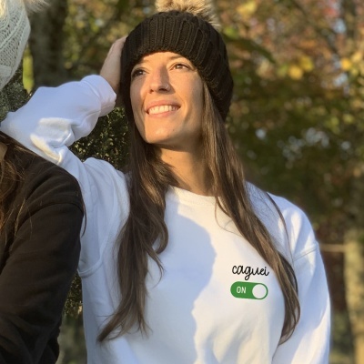 Mulher com sweatshirt branca e gorro castanho ao ar livre