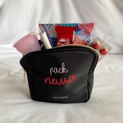 Necessaire preta com itens menstruais e blister de comprimidos