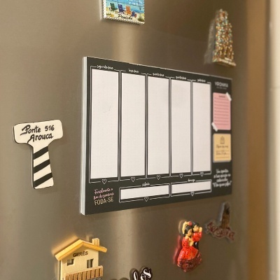 Calendário semanal em imã de frigorífico preto com texto em português, rodeado por ímanes coloridos