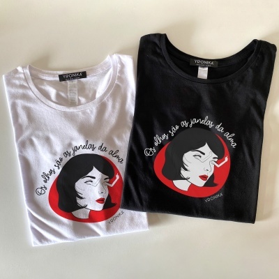 Duas t-shirts, branca e preta, com estampa de mulher e texto em português.