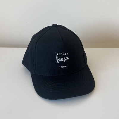 Boné preto com bordado branco 'ALERTA brasa' e 'VPKONG' sobre superfície branca.