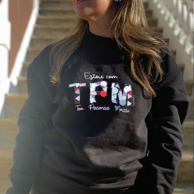Pessoa vestindo sweatshirt preta com texto colorido e padrão floral
