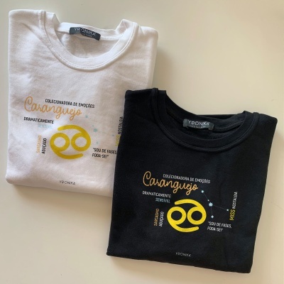 Duas t-shirts dobradas, uma branca e uma preta, com texto e estampagem amarela e branca