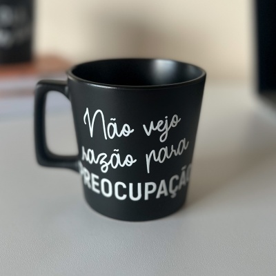 Caneca preta com frase branca 'Não vejo razão para préocupação'