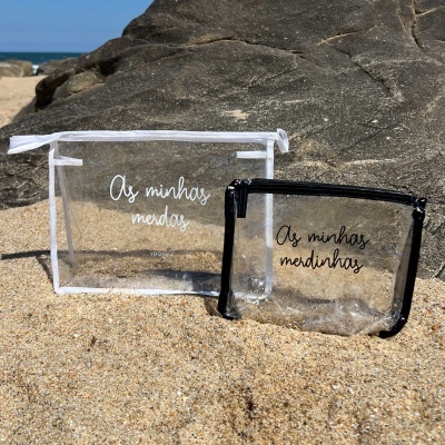 Duas bolsas transparentes com fechos e texto em português na praia
