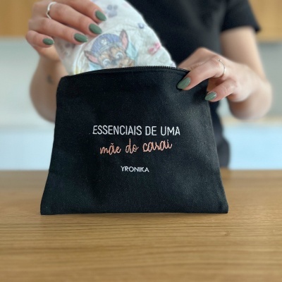 Bolsa preta bordada com texto em mãos femininas a retirar fralda com desenho animado