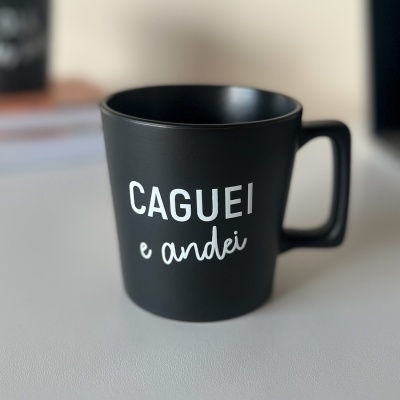 Caneca preta com texto branco CAGUEI e andei