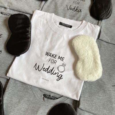 T-shirts com frases em algodão e máscaras para dormir em tecido preto e branco felpudo dispostas sobre uma superfície.