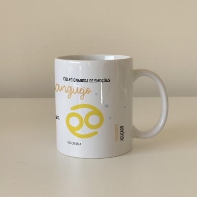 Caneca branca com símbolo amarelo e texto sobre signo de Caranguejo