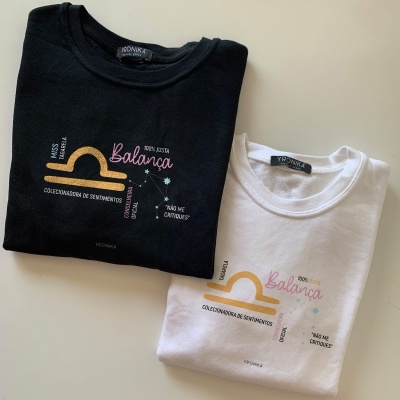 Duas t-shirts, preta e branca, com estampas coloridas da Balança, marca YRONIKA
