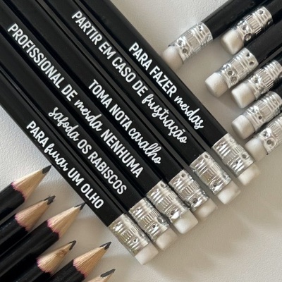 Lápis pretos com inscrições brancas e borrachas brancas sobre fundo claro