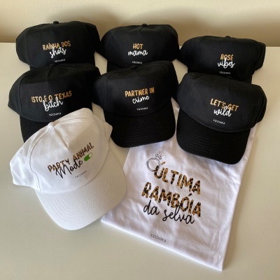 Conjunto de bonés e t-shirt com várias frases bordadas em diferentes cores sobre fundo branco