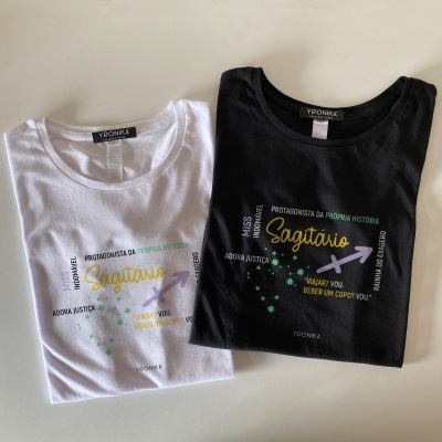 Duas t-shirts, branca e preta, com estampas coloridas e texto em português