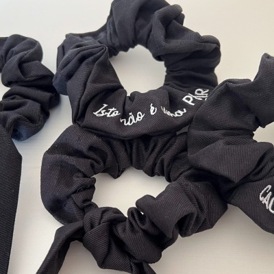 Elásticos de cabelo pretos com bordados em branco sobre superfície branca