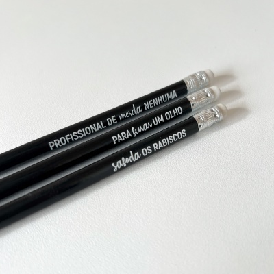 Três lápis pretos com textos brancos e borrachas transparentes