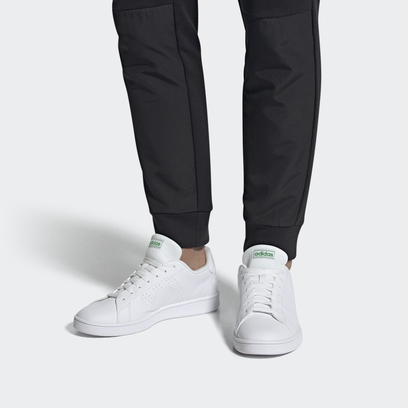 Ténis brancos Adidas com detalhes verdes usados com calças pretas